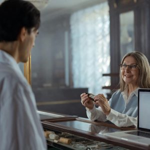 Senior woman pharmacist assisting a customer with a bottle in a vintage pharmacy.